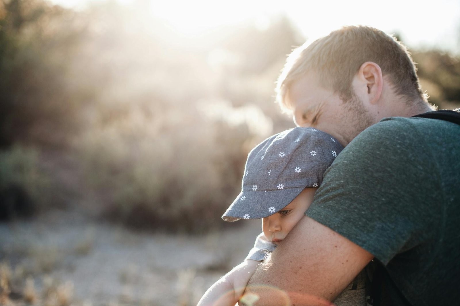 a man hugging his baby on a sunny afternoon Fathers Shape Who We Become