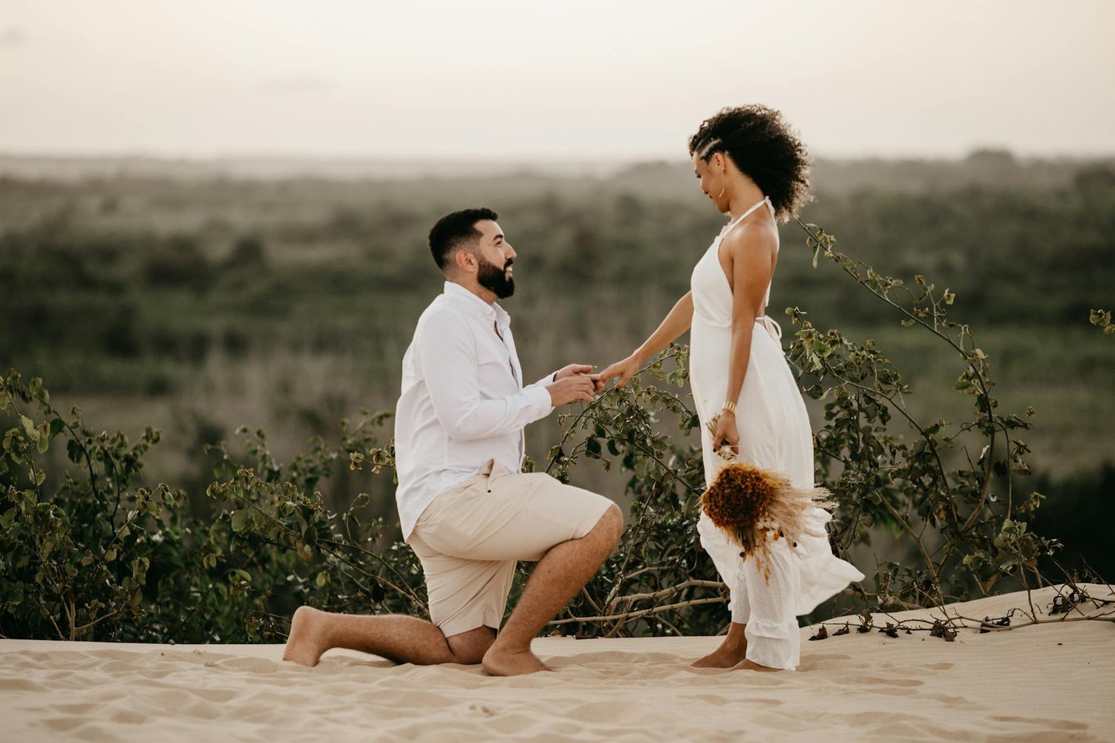 man kneeling and proposing to woman on beach