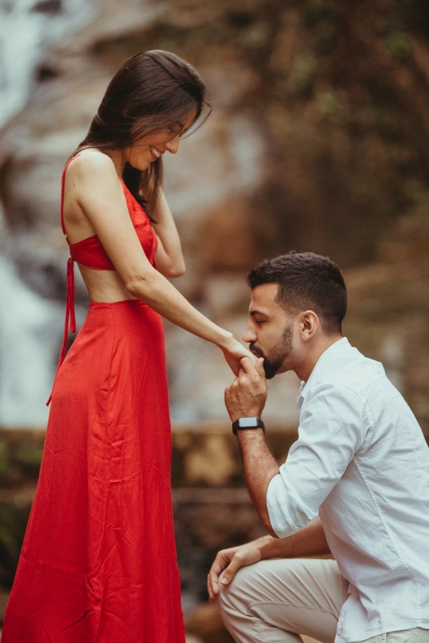 man in white dress shirt kissing woman in red dress