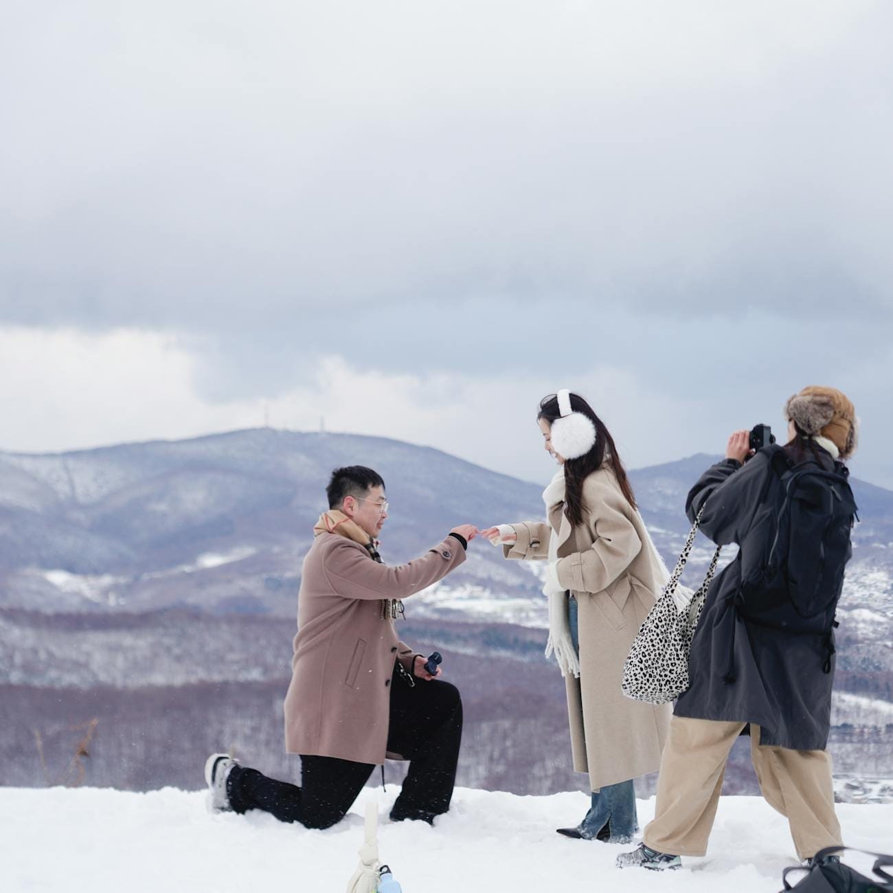 man proposing in snowy mountain landscape