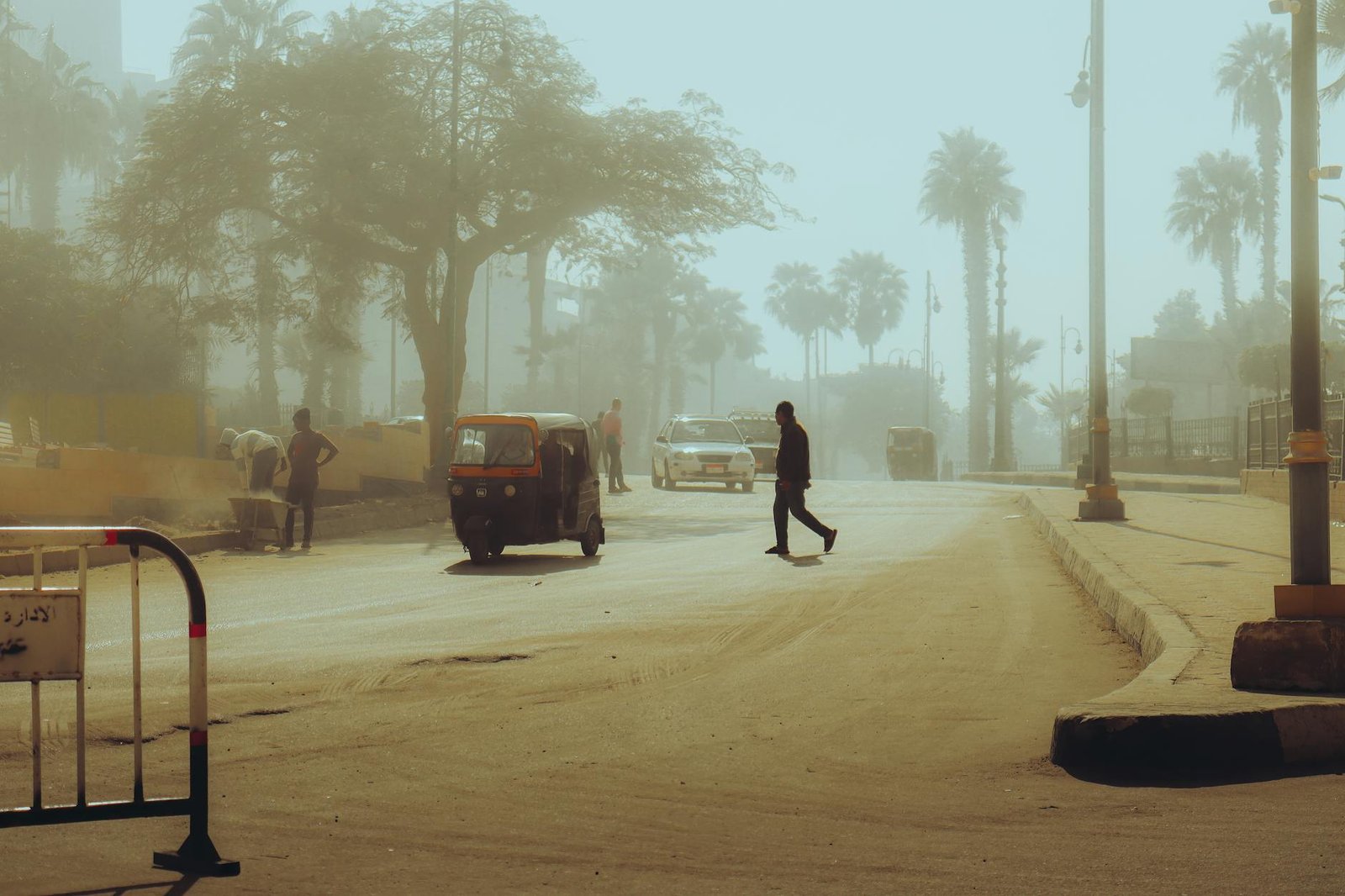 dusty street scene with tuktuk and palm trees