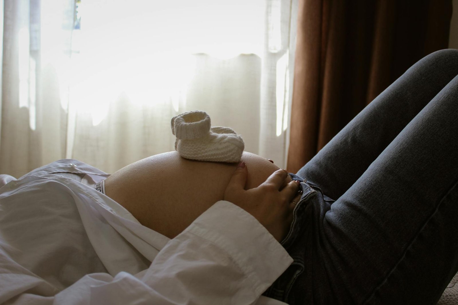pregnant woman relaxing with baby shoes on belly