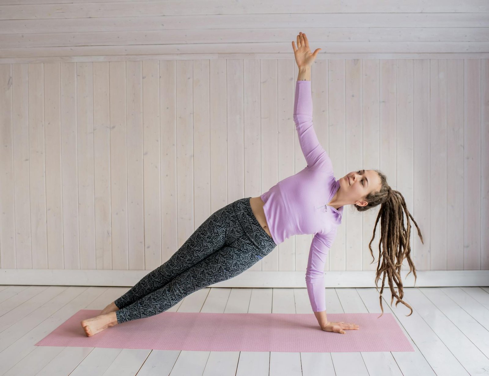woman in pink long sleeve shirt and gray leggings doing yoga