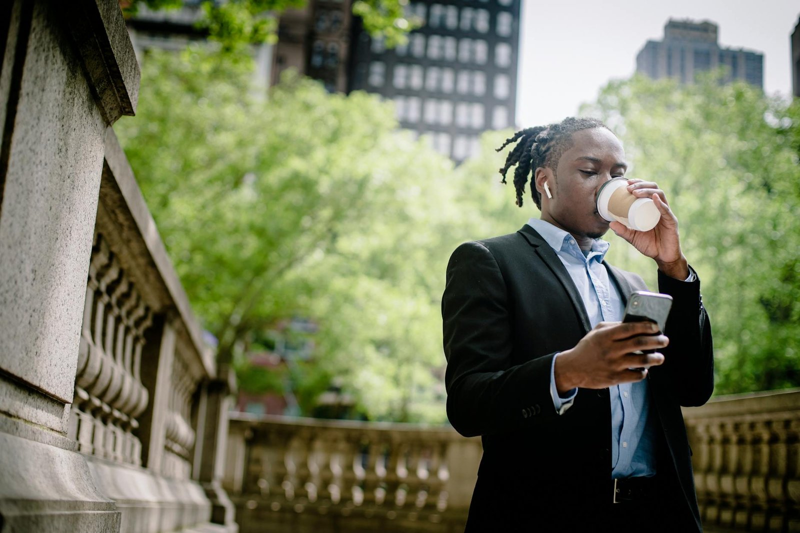 concentrated young male using smartphone during coffee break on street