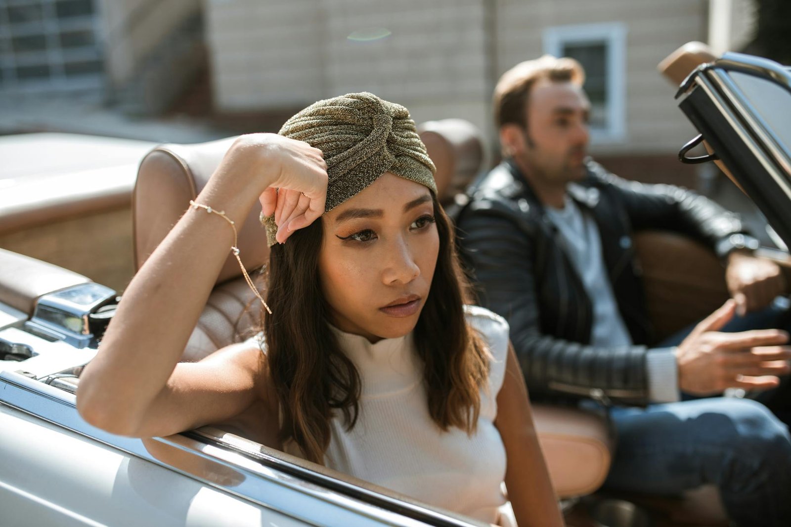 woman in white tank top sitting in a car feeling annoyed
