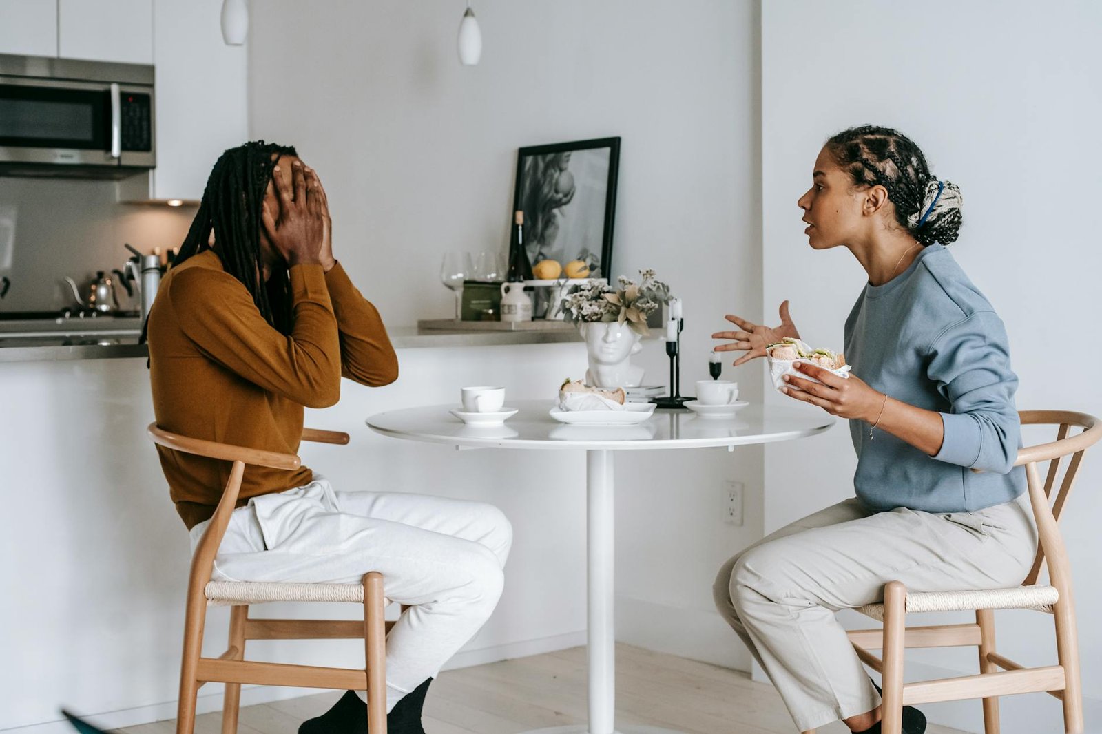 multiethnic couple quarrelling at table in light apartment
