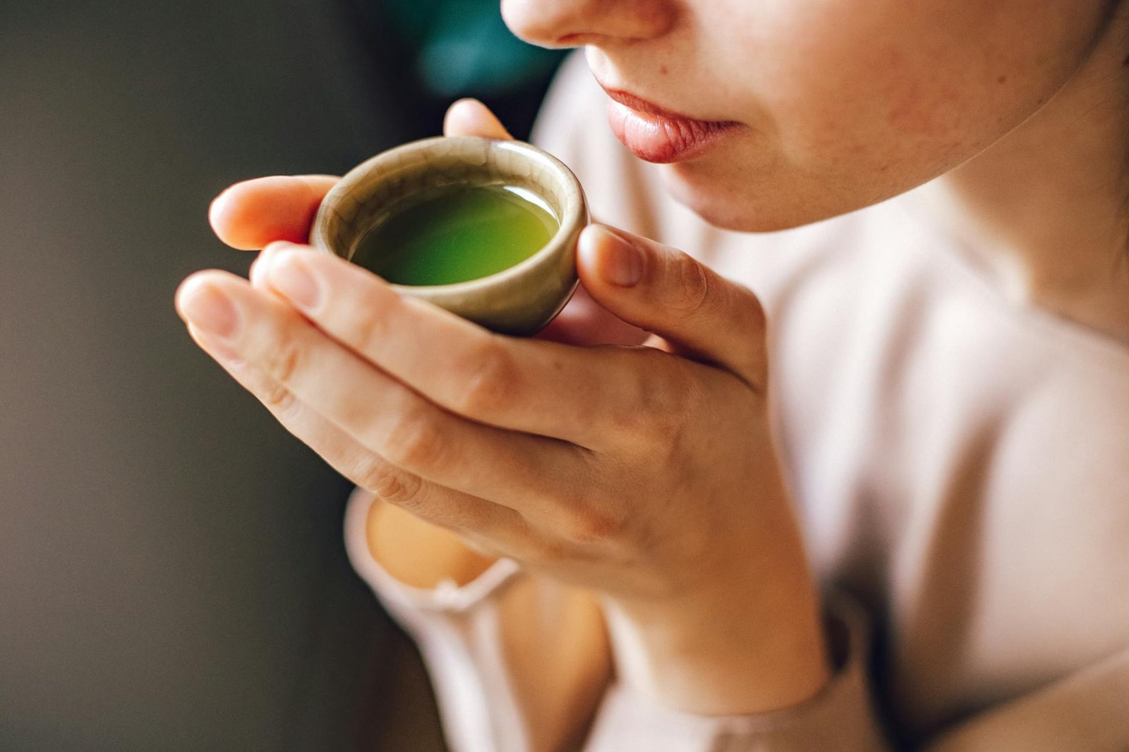 woman holding a small bowl with a match tea
