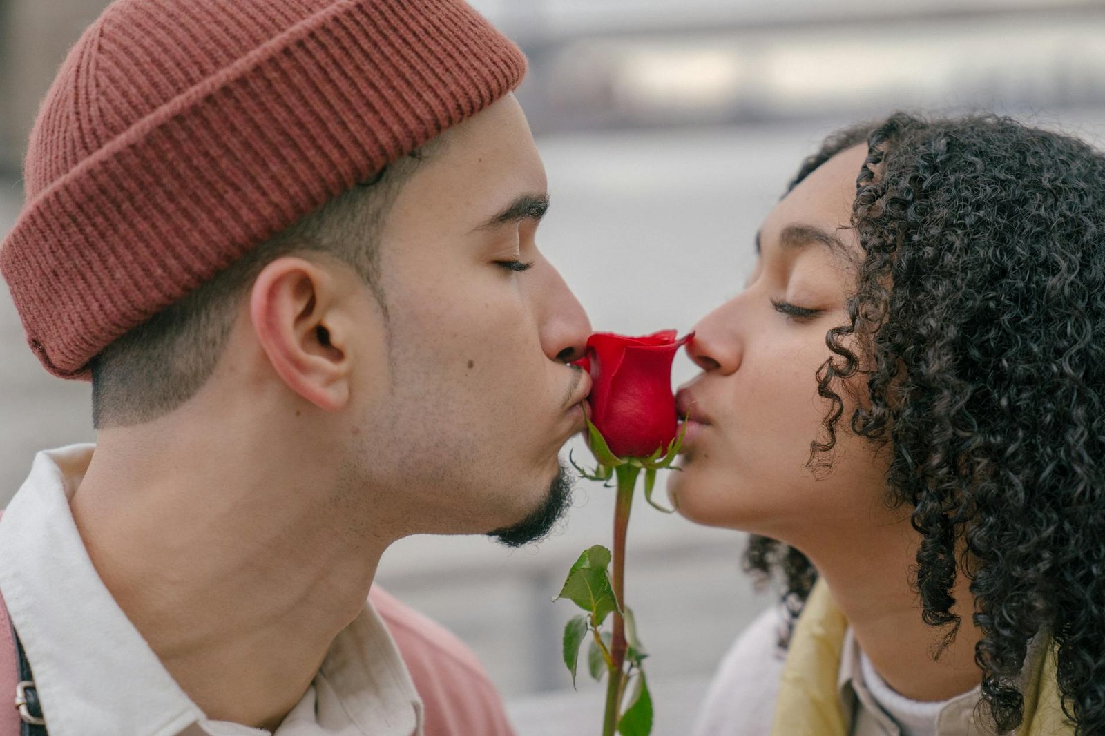 tender hispanic couple kissing rose on waterfront