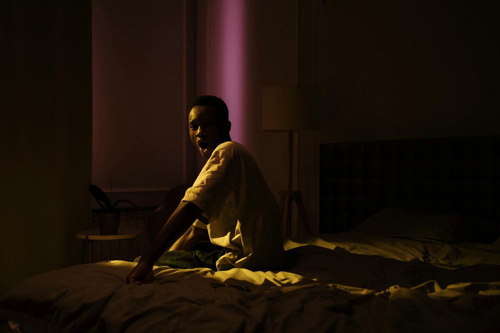 a man sitting on the bed in a dark room