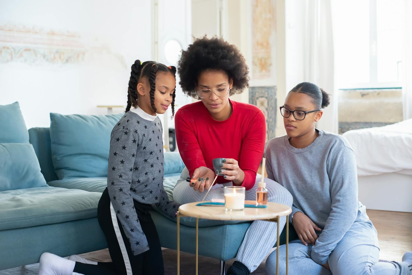 two girls watching their mother make a scented candle