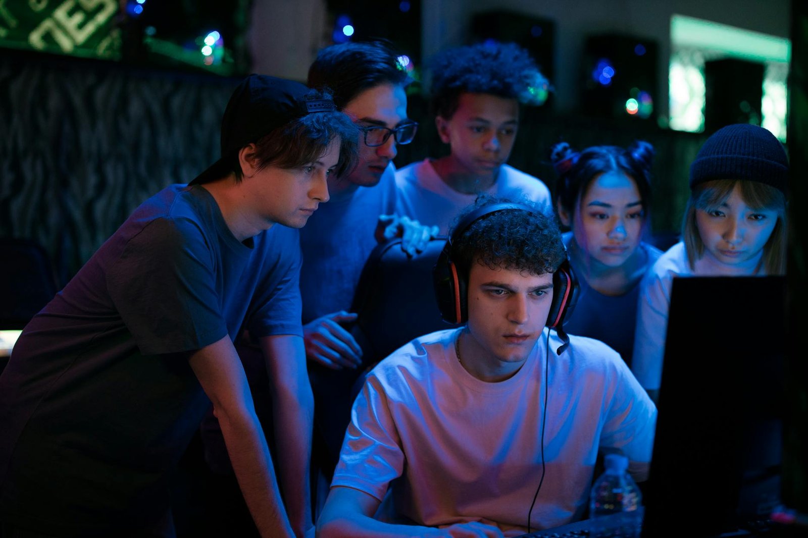 group of teenagers watching a man play game on computer