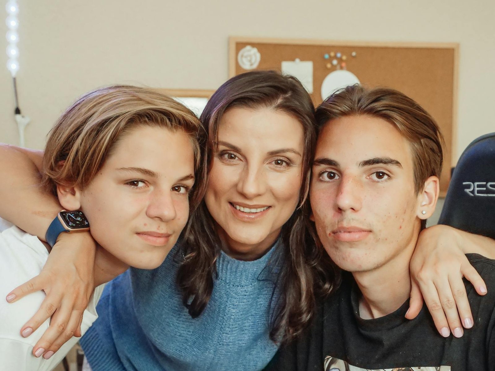 woman in a blue top hugging two boys