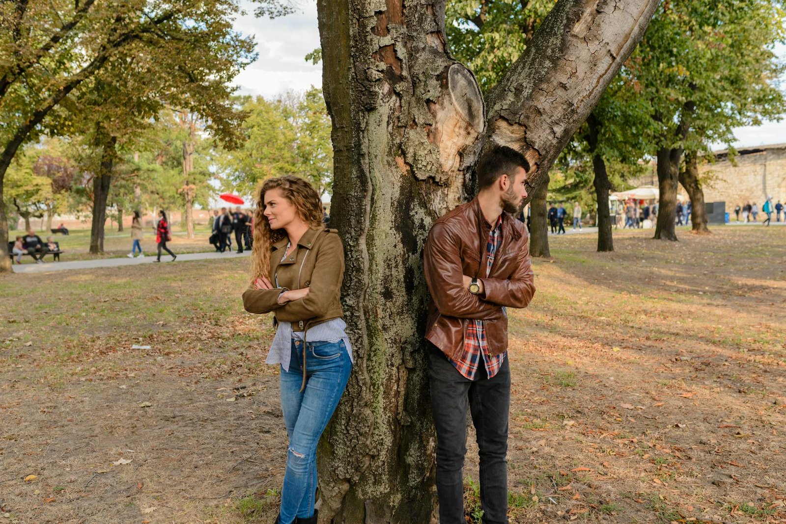 man and woman wearing leather jackets standing under tree