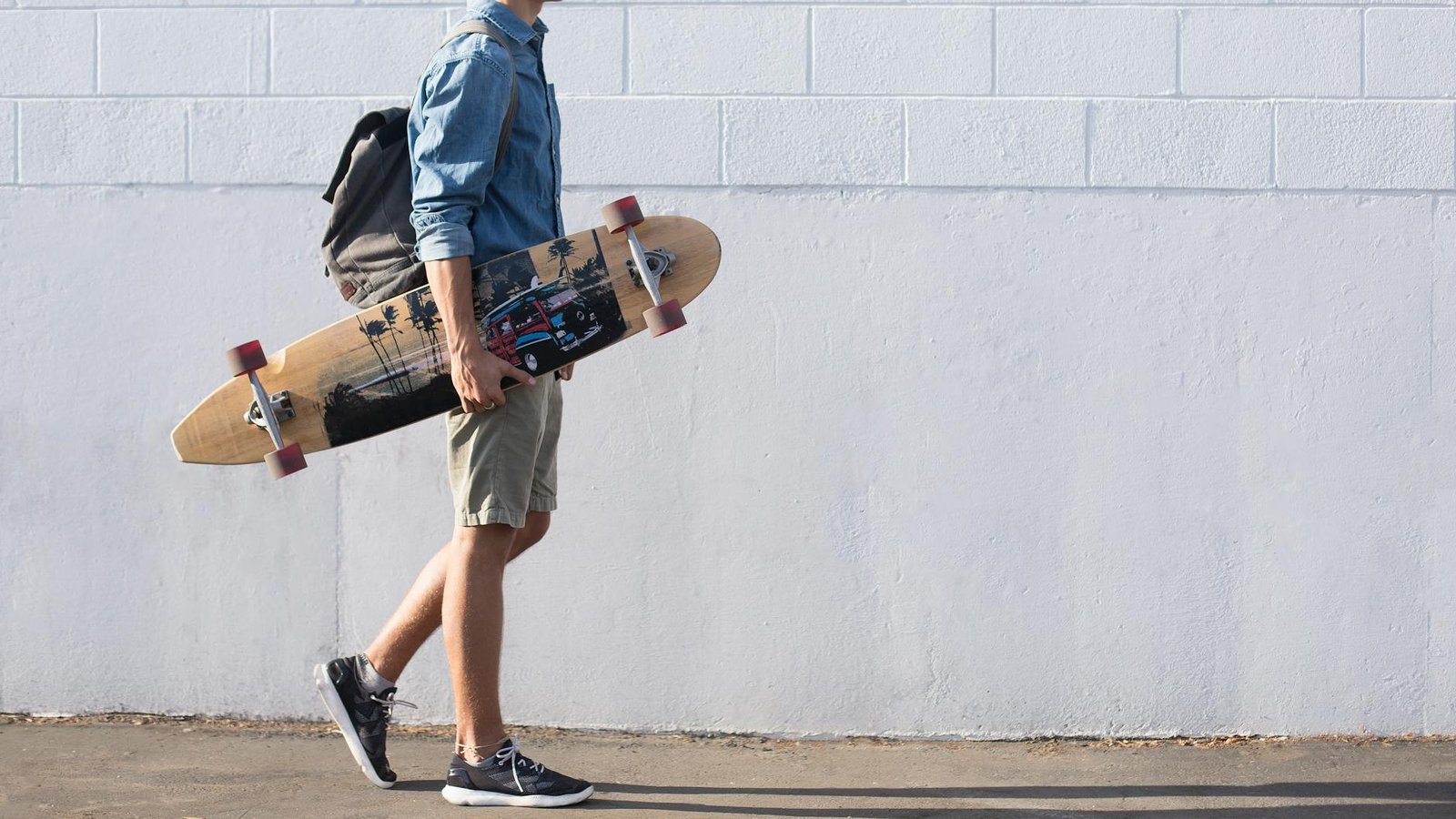 man in blue top carrying a longboard Best Ways to Cope with Loneliness